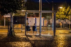 Foto: Zwei Jugendliche warten in der Bushaltestelle auf den Bus